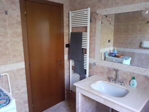 Une salle de bain avec un lavabo, un miroir, un porte-serviettes et une porte.