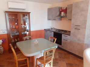 Una cocina compacta con mesa, sillas y un armario con puertas de vidrio.