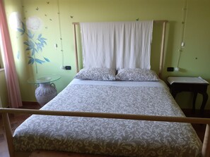 Una cama con dosel, una mesita de noche, un florero y una pared con un mural floral.