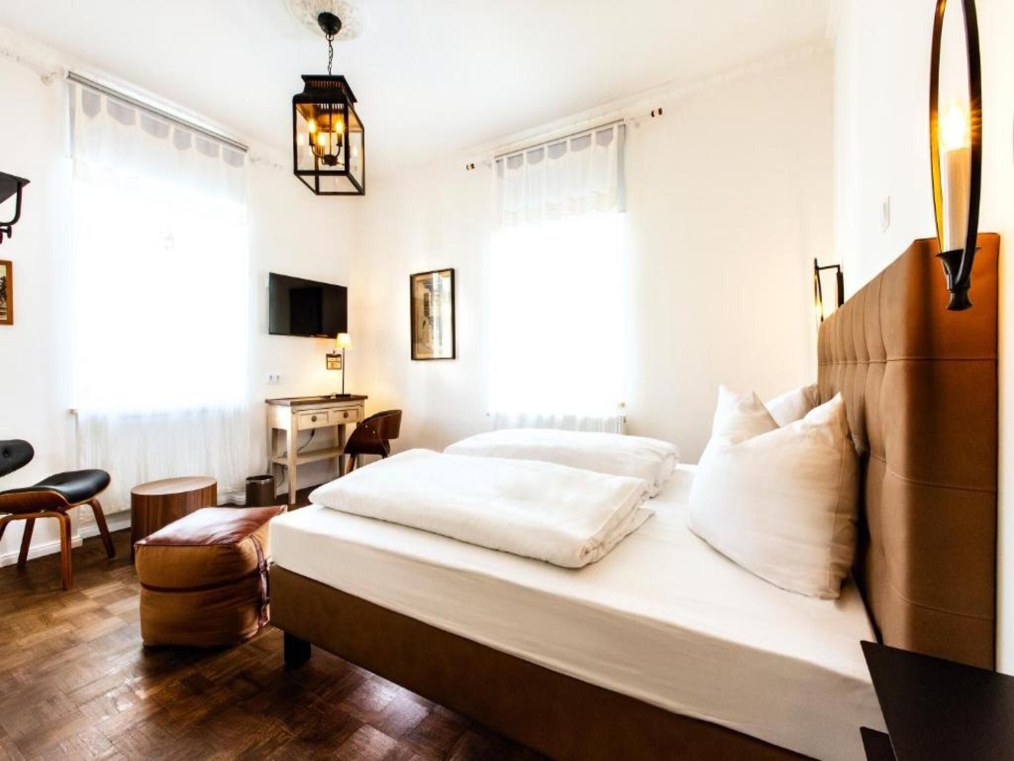 A hotel room with a bed, a desk, a chair, and a television.