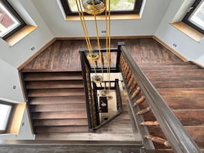 A wooden staircase with a metal railing and a modern light fixture. - Hotel Villa WUN (Wunsiedel)