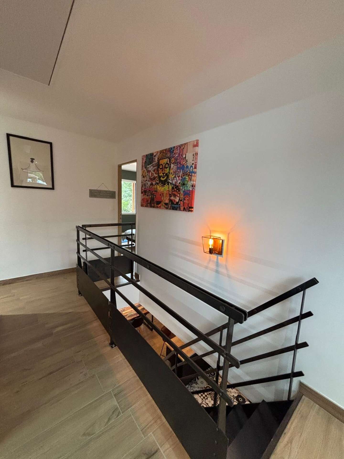 Un escalier avec une rampe métallique menant à un palier.