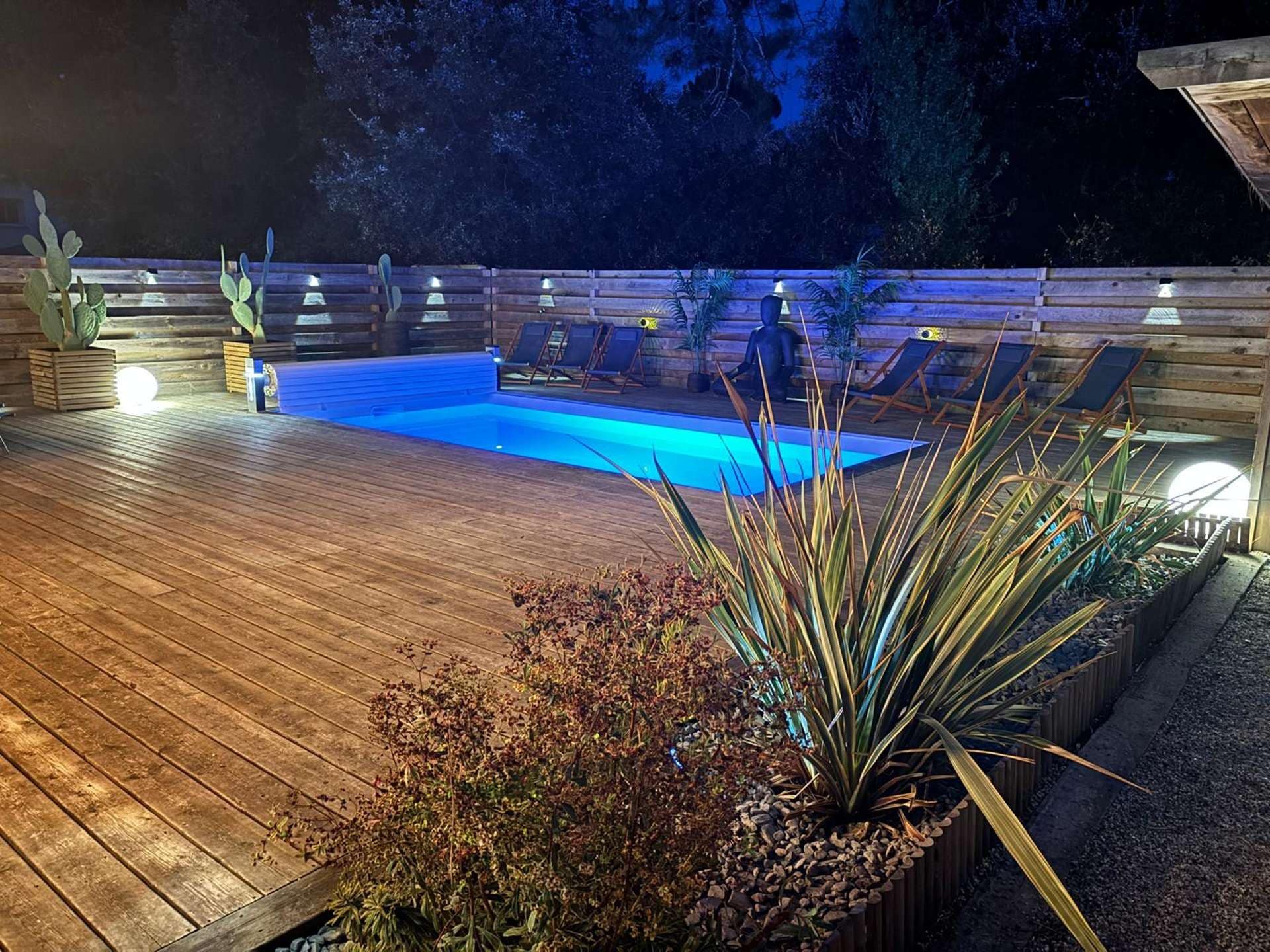 Eine Holzterrasse mit einem Schwimmbecken, umgeben von Pflanzen und Stühlen.