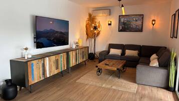 Un salon moderne avec un téléviseur à écran plat, un meuble en bois, un canapé et une table basse.