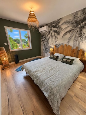 Une chambre à coucher avec un lit, une peinture murale, une fenêtre et un luminaire suspendu.
