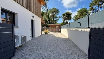 Un bâtiment moderne avec une allée de gravier menant à un portail en bois.