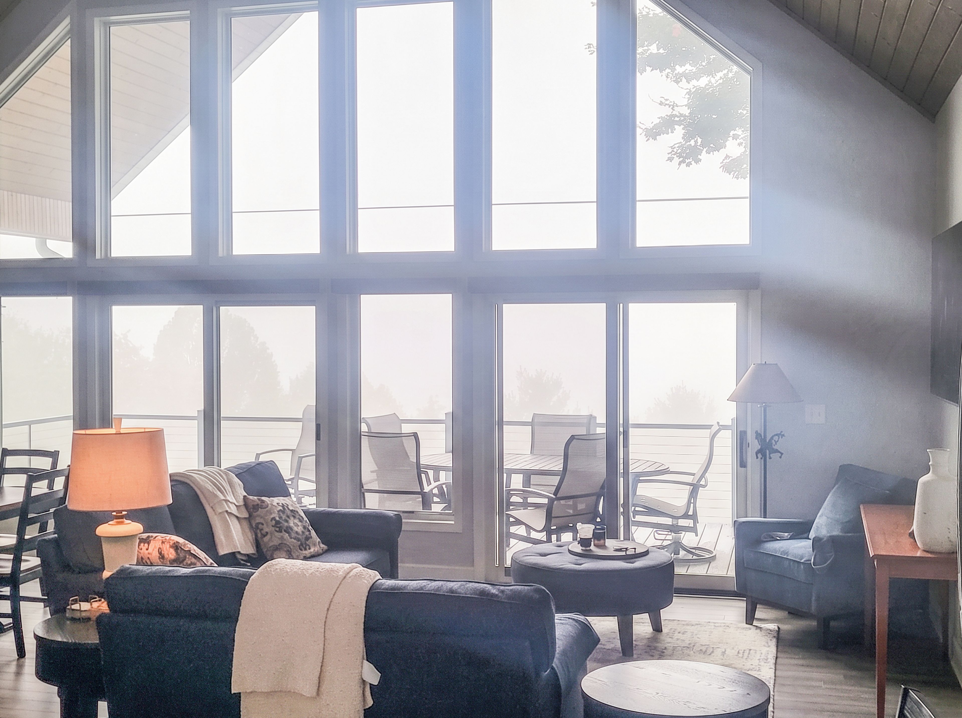 A spacious living area with a large window, a sofa, a coffee table, and a lamp.