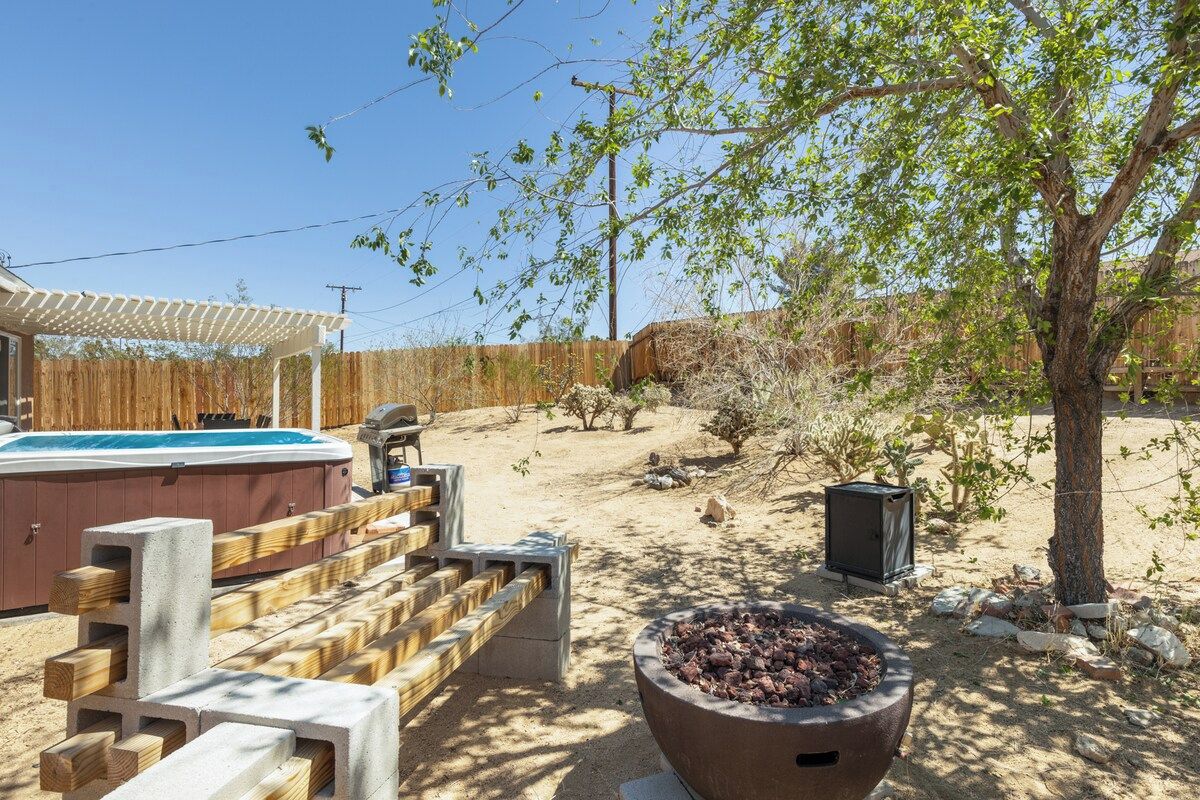 A backyard with a hot tub, a fire pit, and a wooden deck.