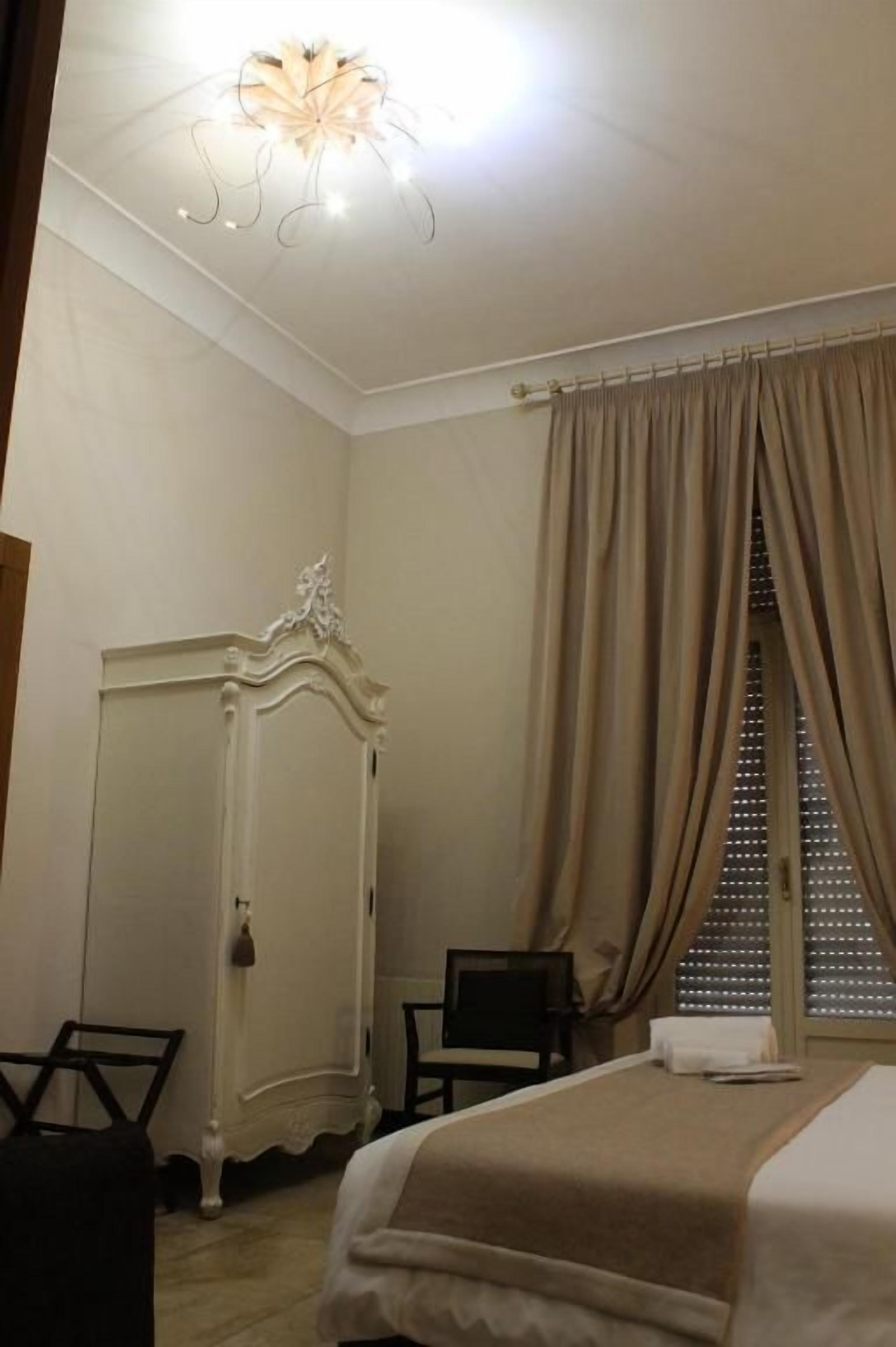 Une chambre à coucher avec un lit, une armoire, un bureau et une fenêtre avec des rideaux.