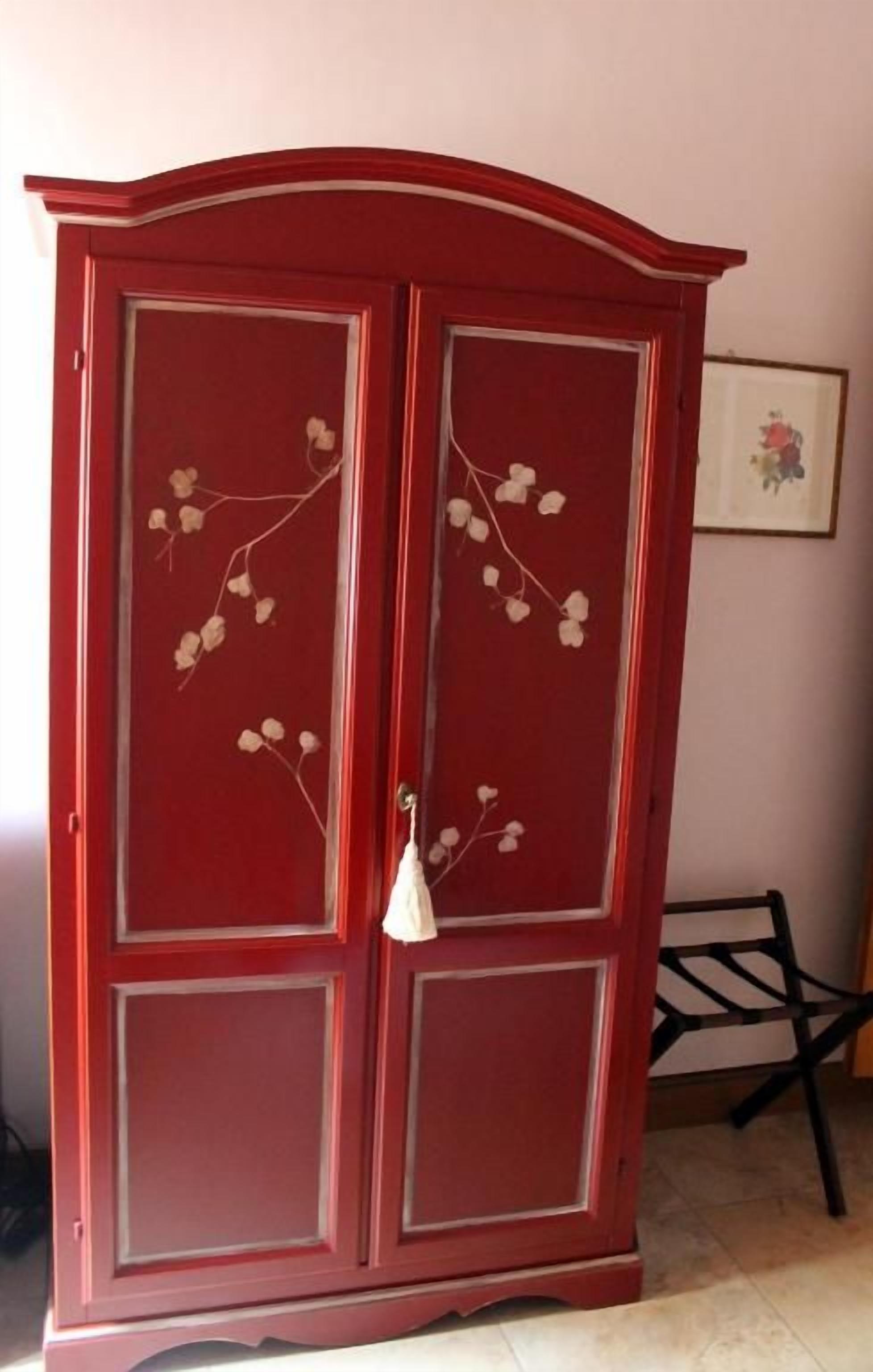 Un meuble rouge avec des portes en verre et des motifs floraux.