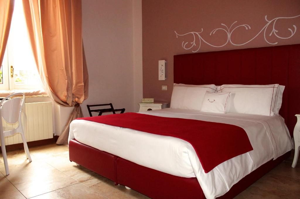 Une chambre à coucher avec une couvre-lit rouge, une chaise blanche et une table de chevet.