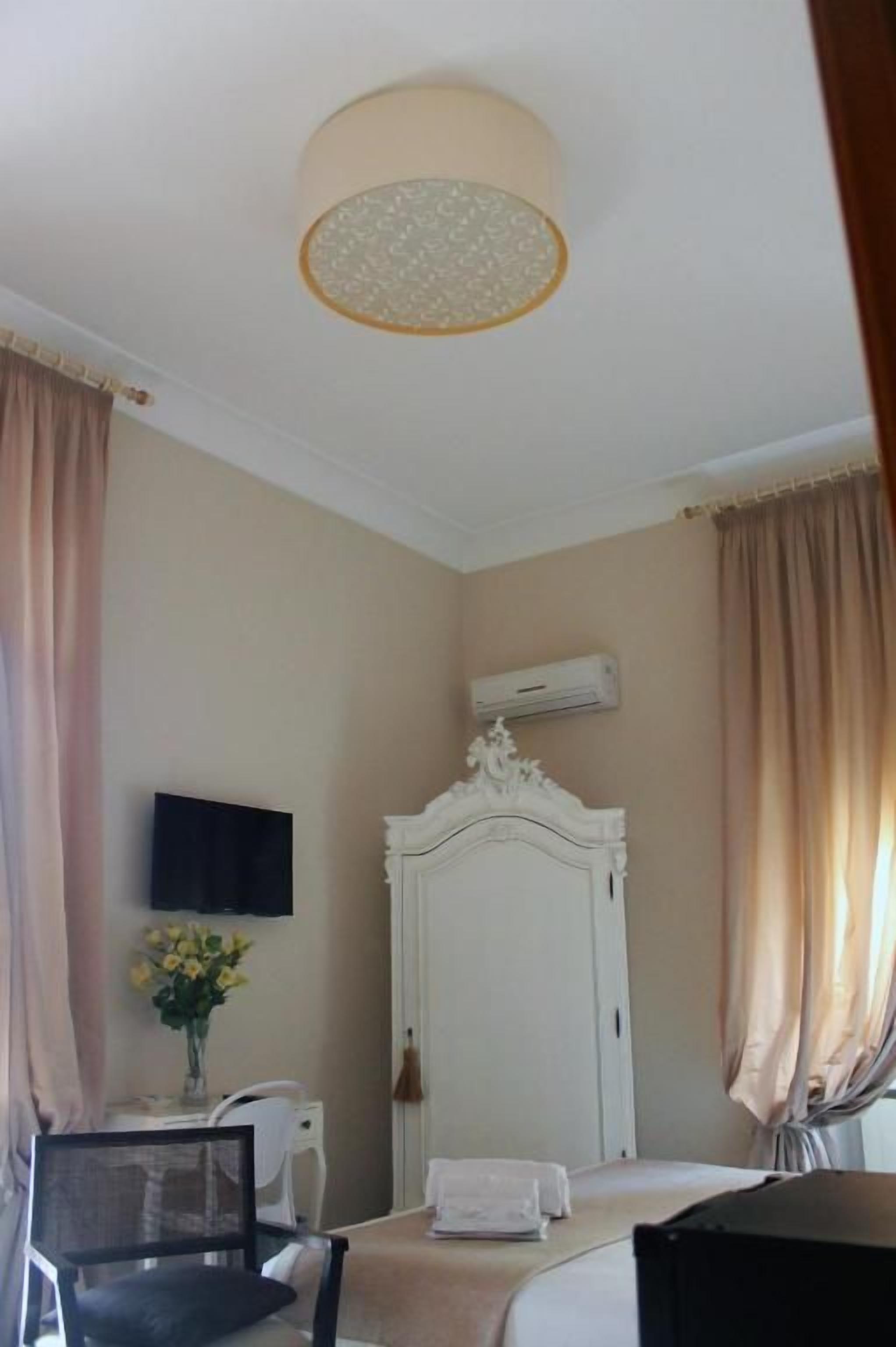 Une chambre d’hôtel équipée d’un lit, d’un bureau, d’une chaise, d’une télévision, d’un climatiseur et de rideaux.