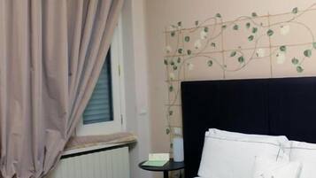 Ein Hotelzimmer mit einem Bett, einem Nachttisch, einem Fenster mit Vorhängen und einer Wanddekoration.