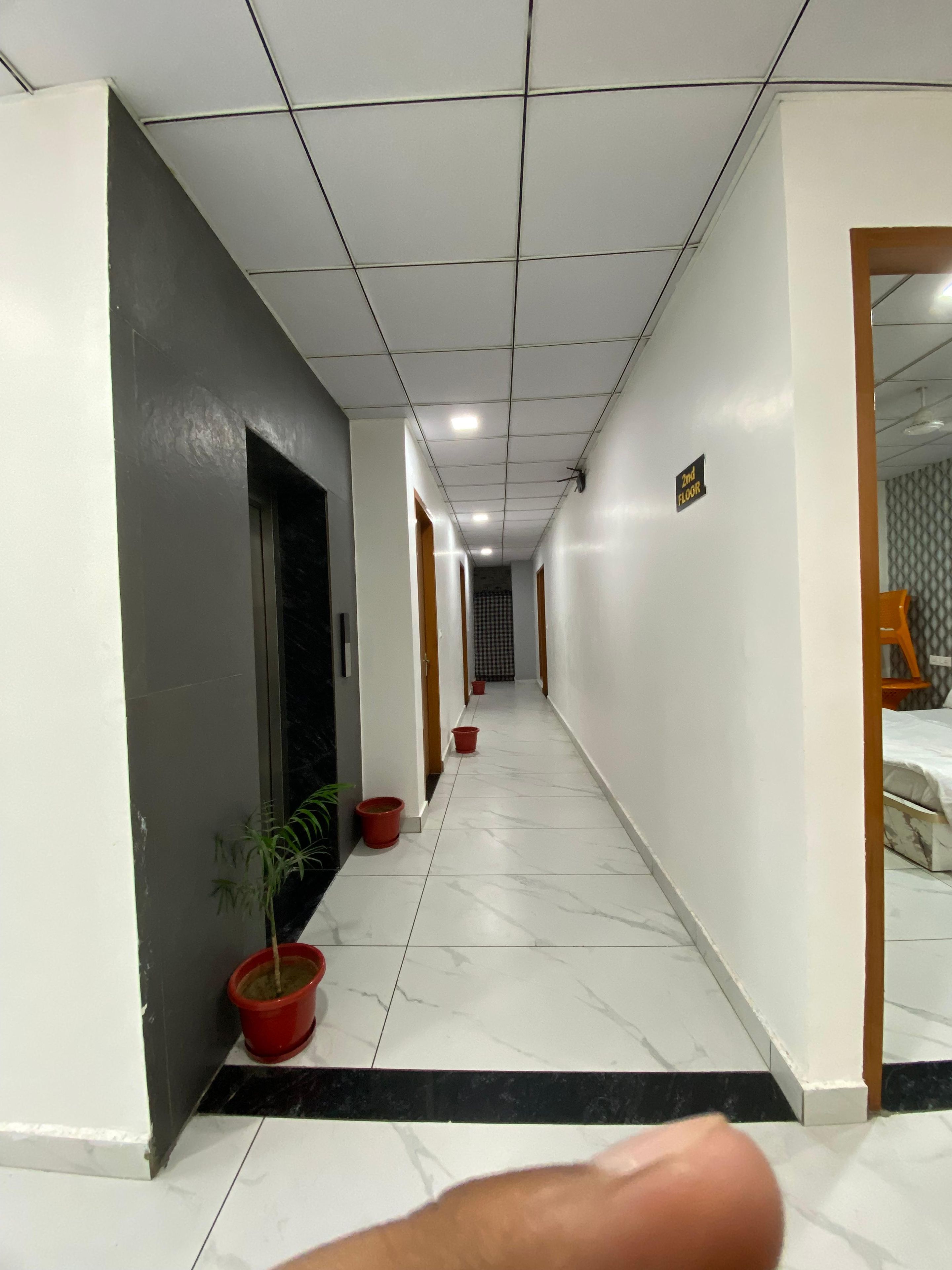 Un pasillo con piso de baldosas, plantas en macetas y un letrero que indica el segundo piso.