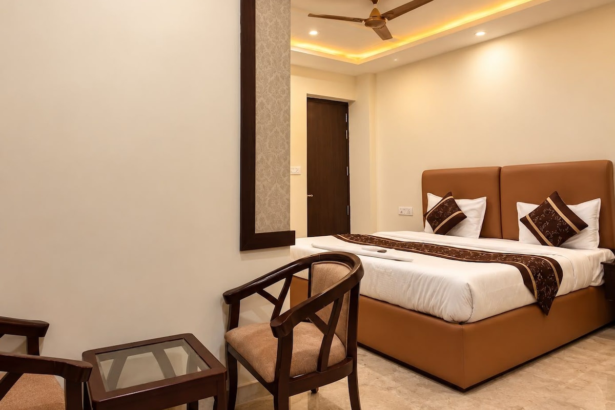 Une chambre à coucher avec un lit, une chaise, une table, un ventilateur de plafond et une porte.