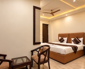 Une chambre à coucher avec un lit, une chaise, une table, un ventilateur de plafond et une porte.