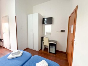 A room with two beds, a desk, a chair, a television, and a wardrobe. - Oasi San Francesco (Roma)