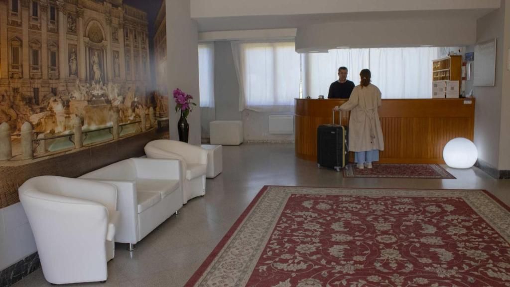 A hotel lobby with a reception desk, seating area, and a large mural.