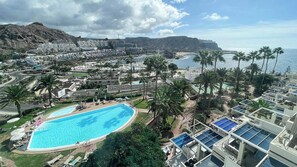 Un resort con una amplia piscina, varias habitaciones para huéspedes y vistas a la costa.