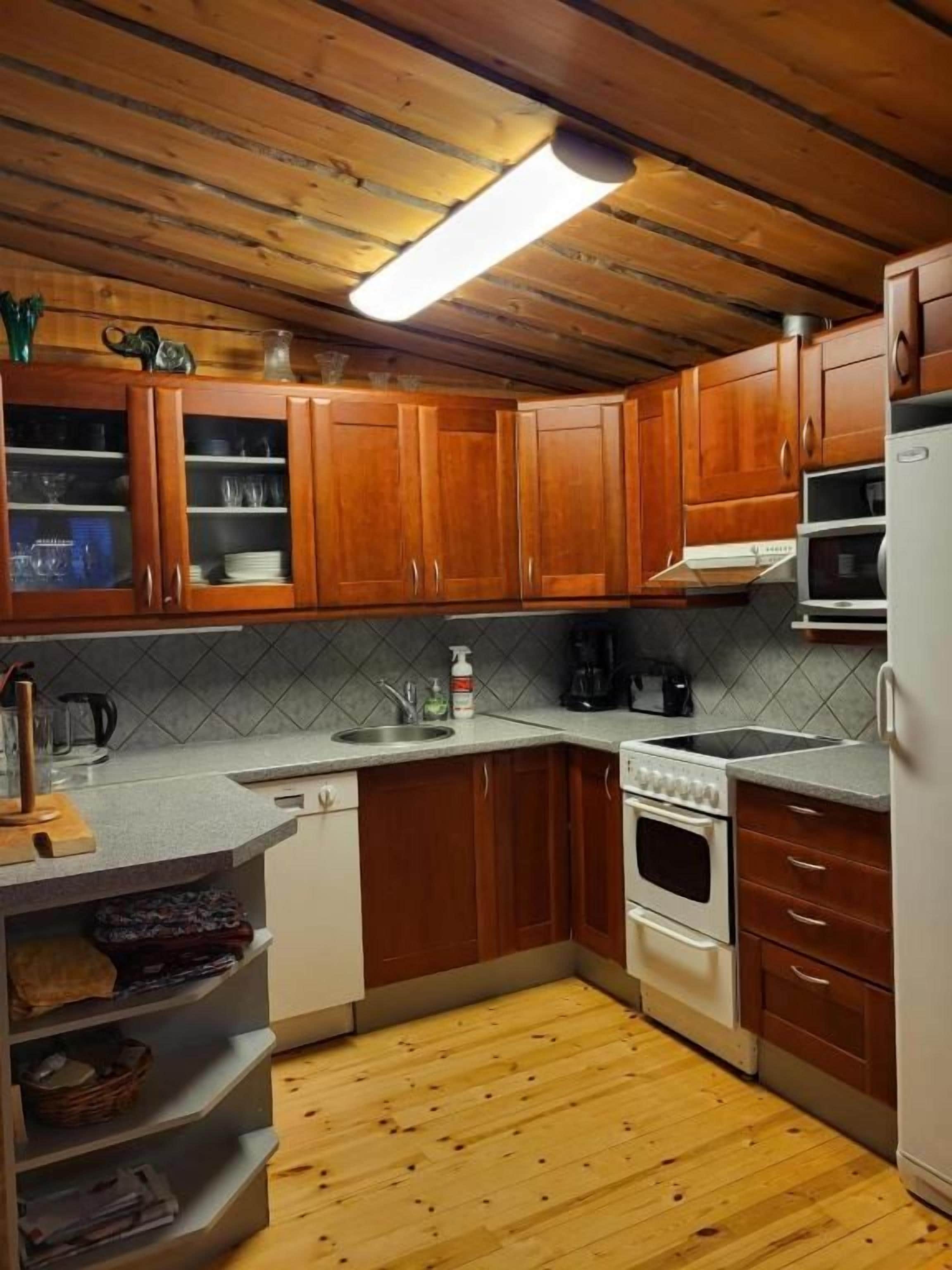 A kitchen with wooden cabinets, a microwave, a stove, and a sink.