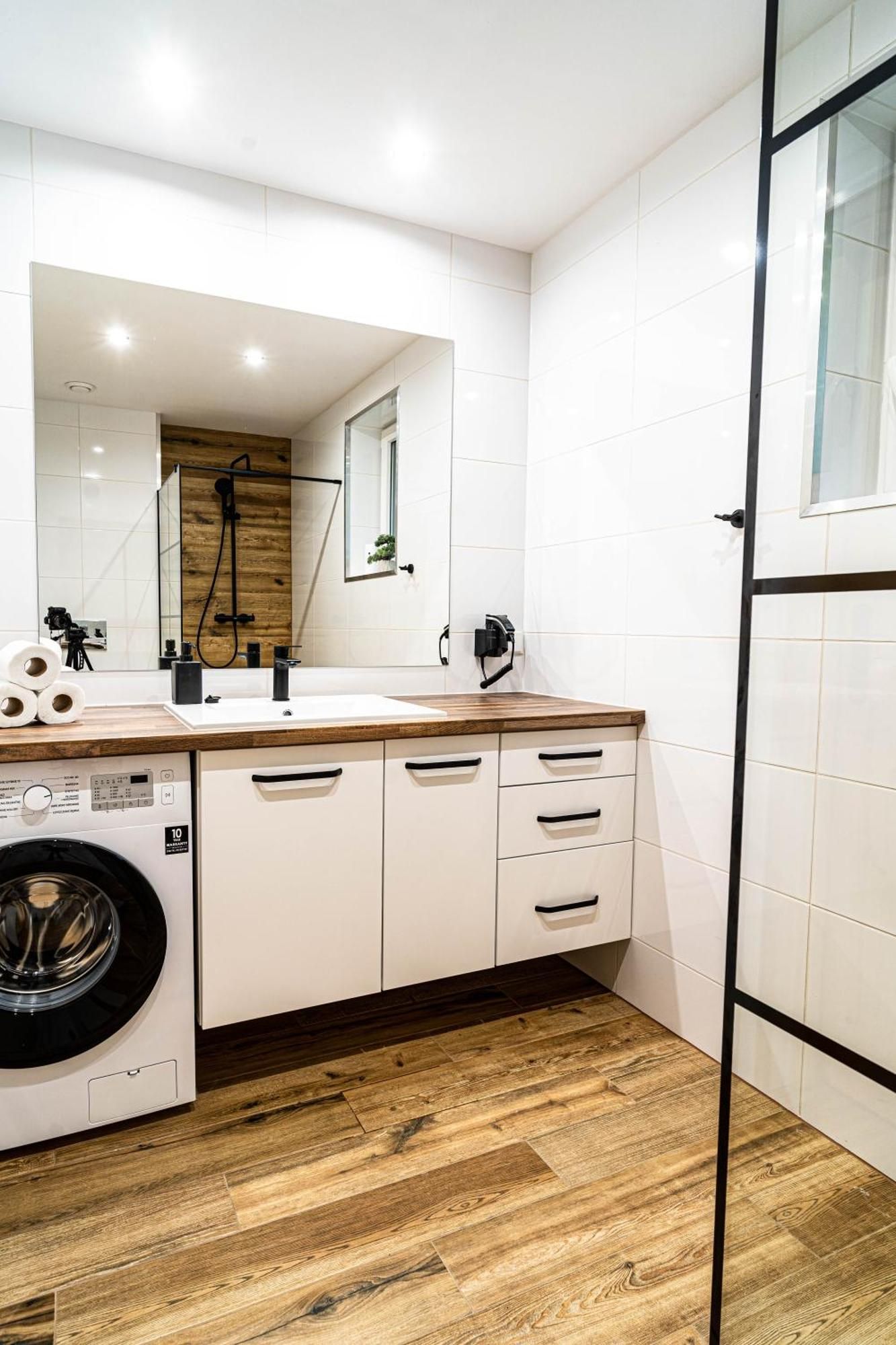 Ein modernes Badezimmer mit Waschmaschine, Waschbecken und Spiegel.