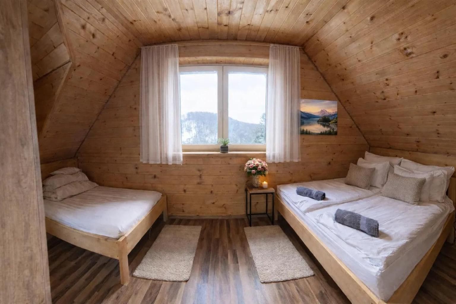 A cozy attic bedroom with two beds, a window with curtains, a small table with a vase, and a painting on the wall.