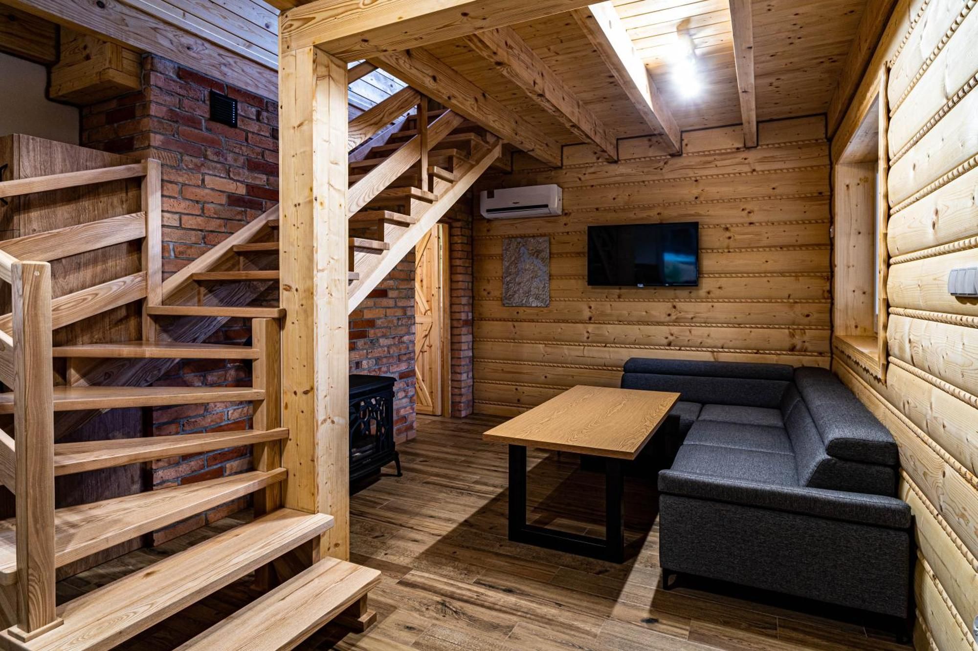 A wooden interior with a staircase, a flat-screen TV, and a sofa.
