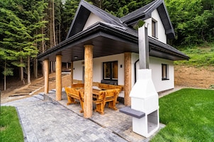 Una casa moderna con un porche cubierto, muebles de madera y un camino de piedra que lleva a la entrada.