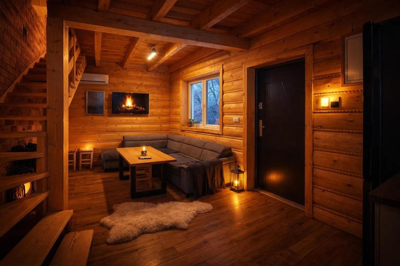 A cozy log cabin interior with a fireplace, a sofa, a table, and a window.