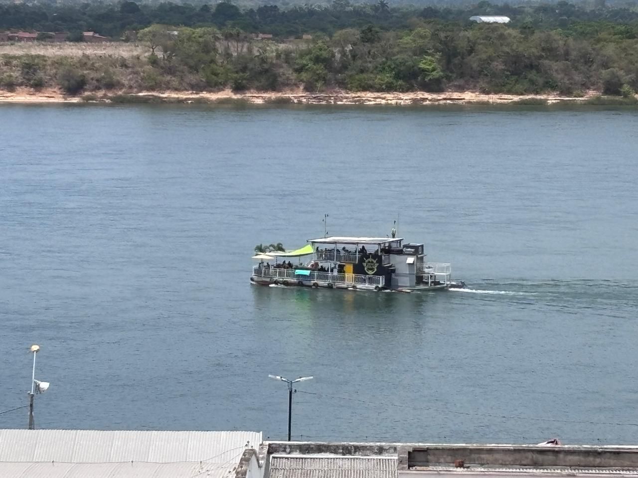 Un barco de recreo con cubierta techada y una bandera, navegando sobre aguas tranquilas.