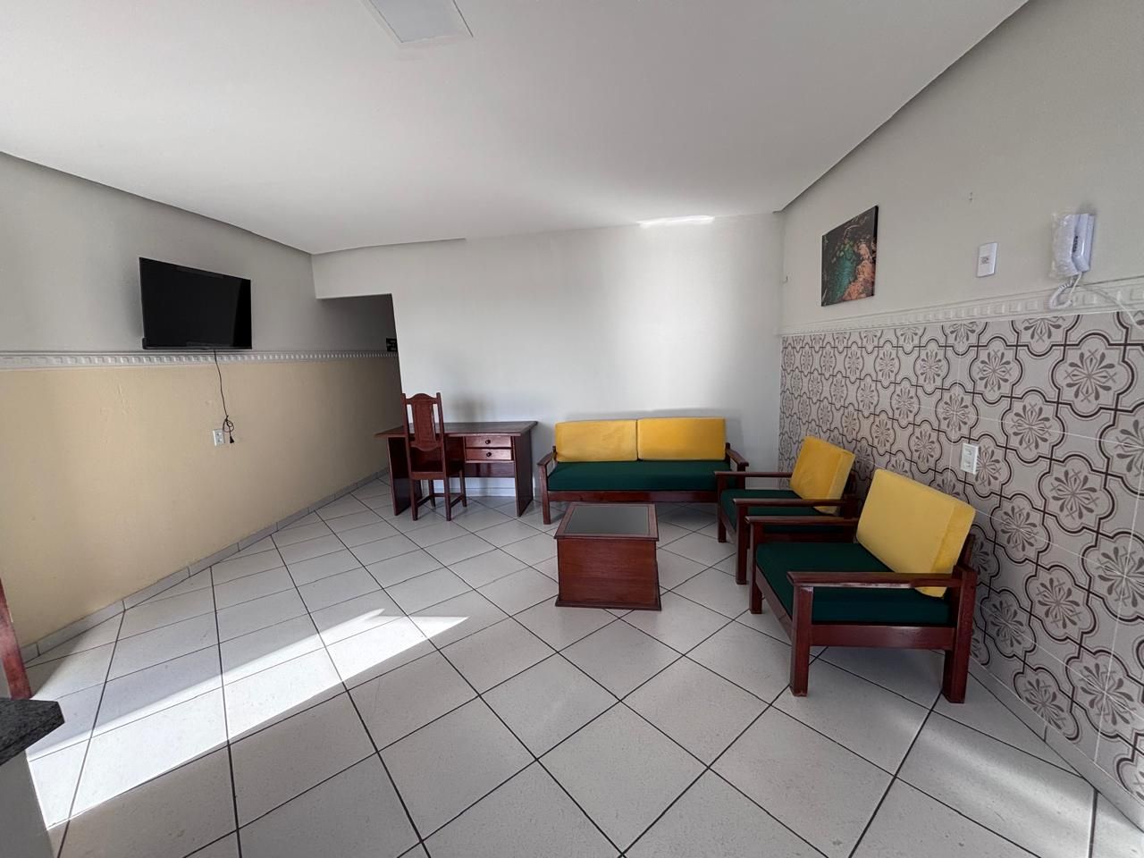 Una habitación con sofá, sillas, una mesita, televisor y paredes con diseño.