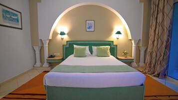 A hotel room with a large bed, two bedside lamps, a nightstand, a framed picture on the wall, and a curtain.