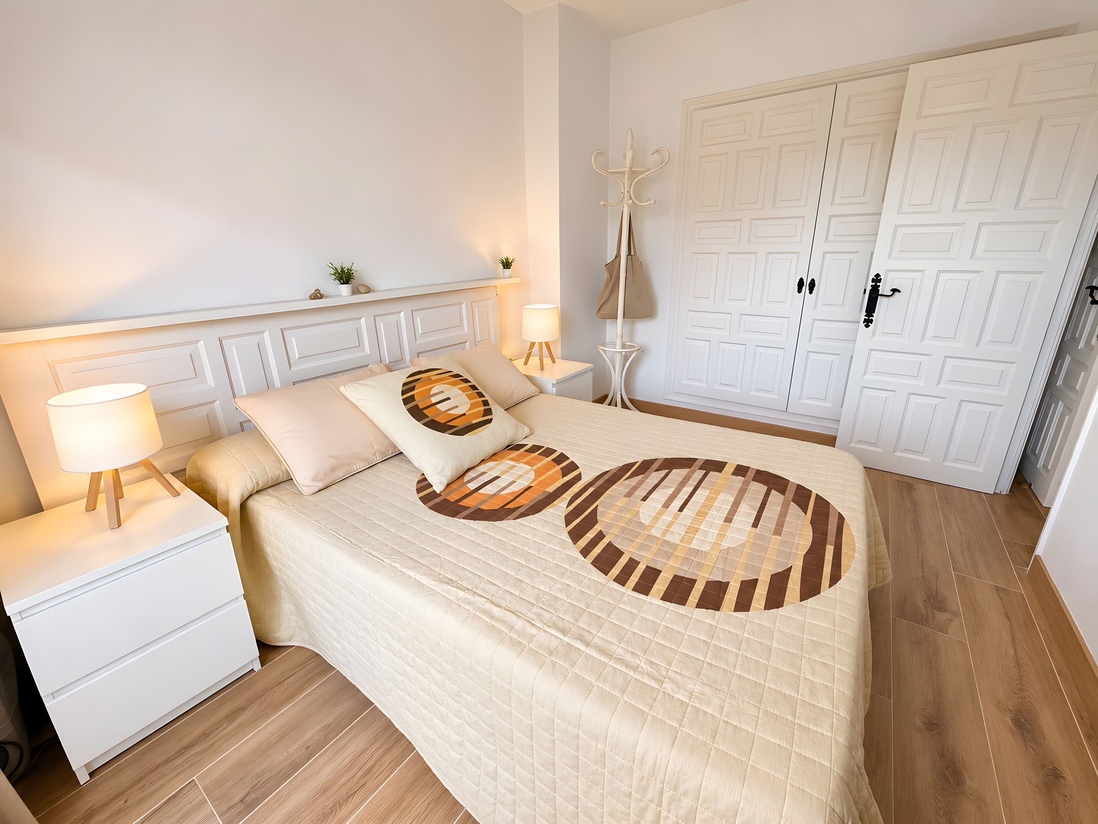 Une chambre à coucher bien rangée, avec un lit, des tables de chevet, une lampe, un porte-manteau et une armoire.