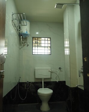 Un baño con inodoro, ducha y ventana con barrotes.