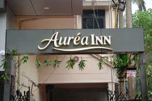 Un letrero de hotel con el nombre 'Auréa INN' y plantas colgantes decorativas.