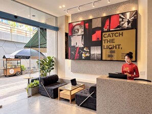 A modern interior with a reception desk, seating area, and a large abstract artwork. - SHANKEE Hotel Nguyen Thai Hoc (Ben Thanh)