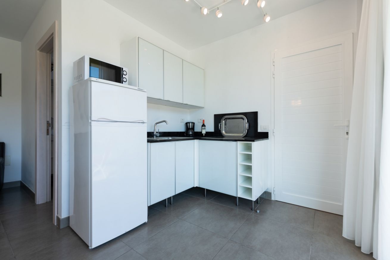 Una cucina moderna con mobili bianchi, un piano di lavoro nero, un forno a microonde e un frigorifero.