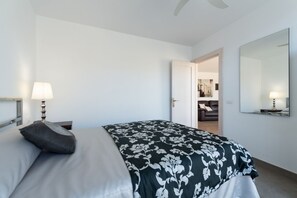 Habitació d'hotel amb un llit, una làmpada de nit, una porta que dona a un passadís i un mirall gran a la paret.