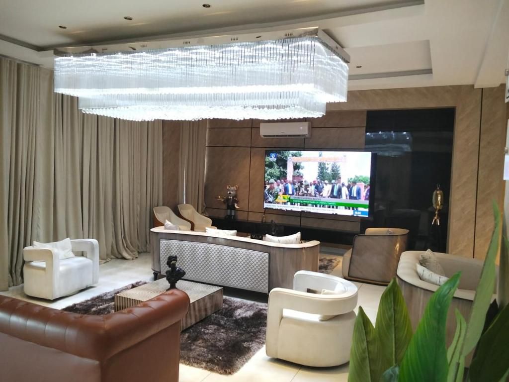 Una sala de estar moderna con un televisor de pantalla plana grande, una araña y muebles contemporáneos.