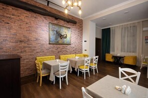 Comedor con paredes de ladrillo, asientos tipo cabina amarillos y mesas blancas.