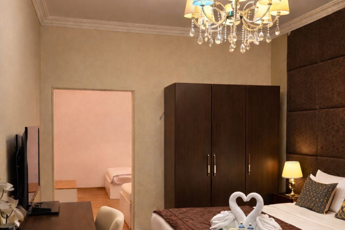 Una habitación de hotel con una cama, un escritorio, una silla, un armario y una araña.