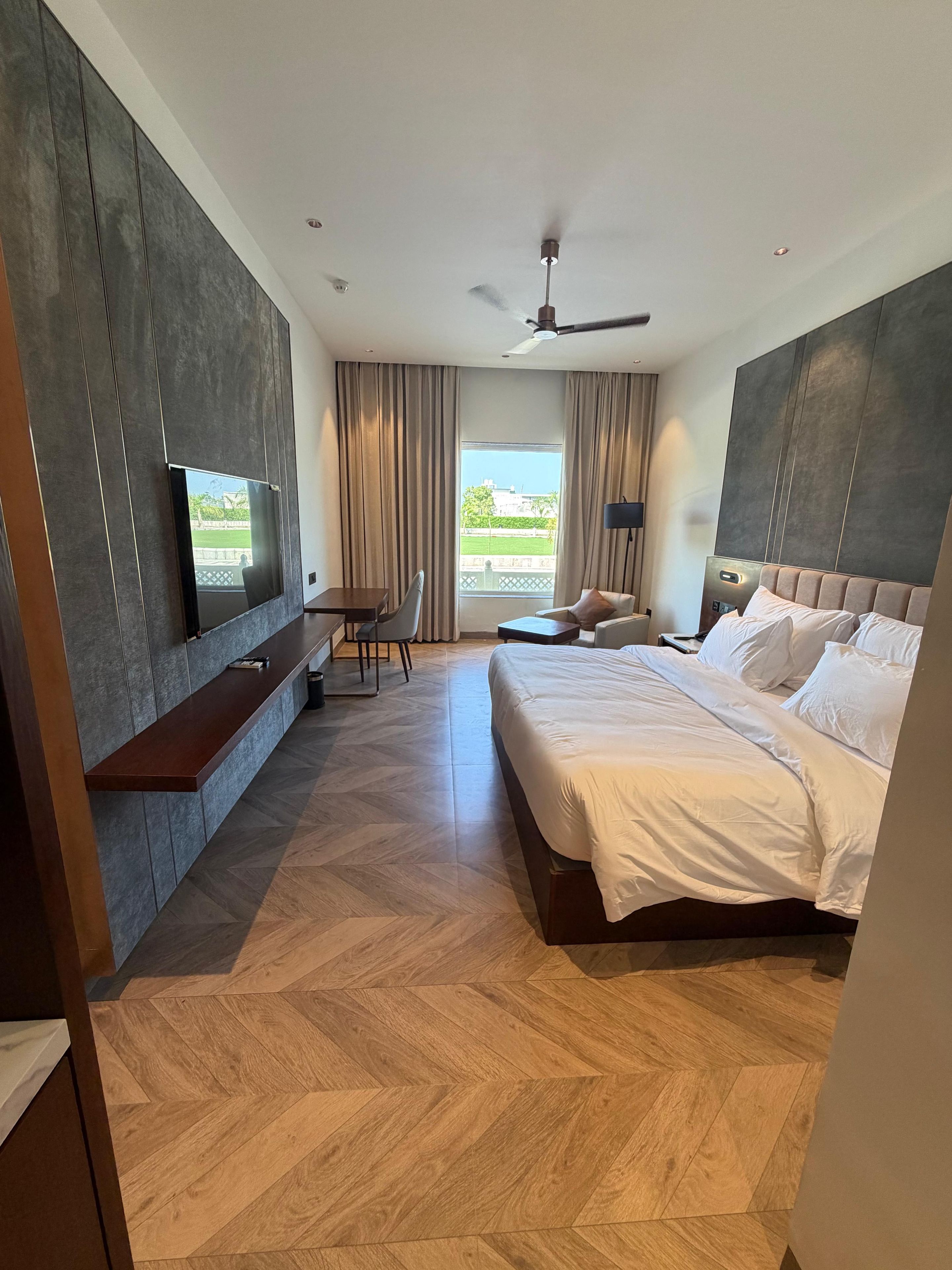 Una camera d'albergo moderna con un letto grande, una scrivania e una TV a parete.