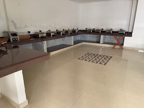 A kitchen area with a long counter, multiple cooking stations, and a tiled floor.