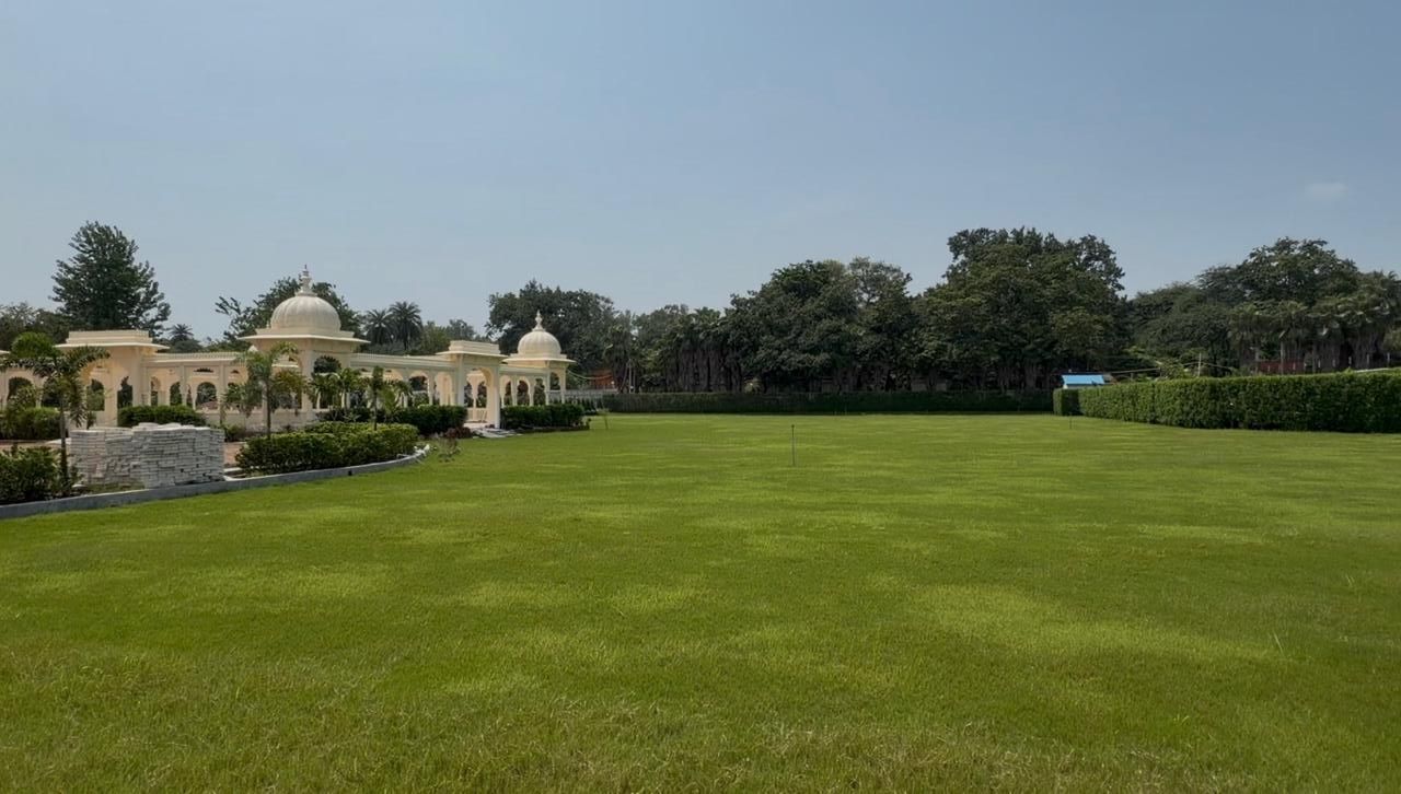 A large, well-maintained lawn with a building featuring domed structures in the background.