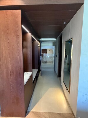 A corridor with wooden paneling on one side, a bench, and a large mirror on the other.