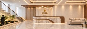 A hotel reception area with a marble reception desk, a sofa, and a staircase. - Sai Shree Hotel (Shirdi)