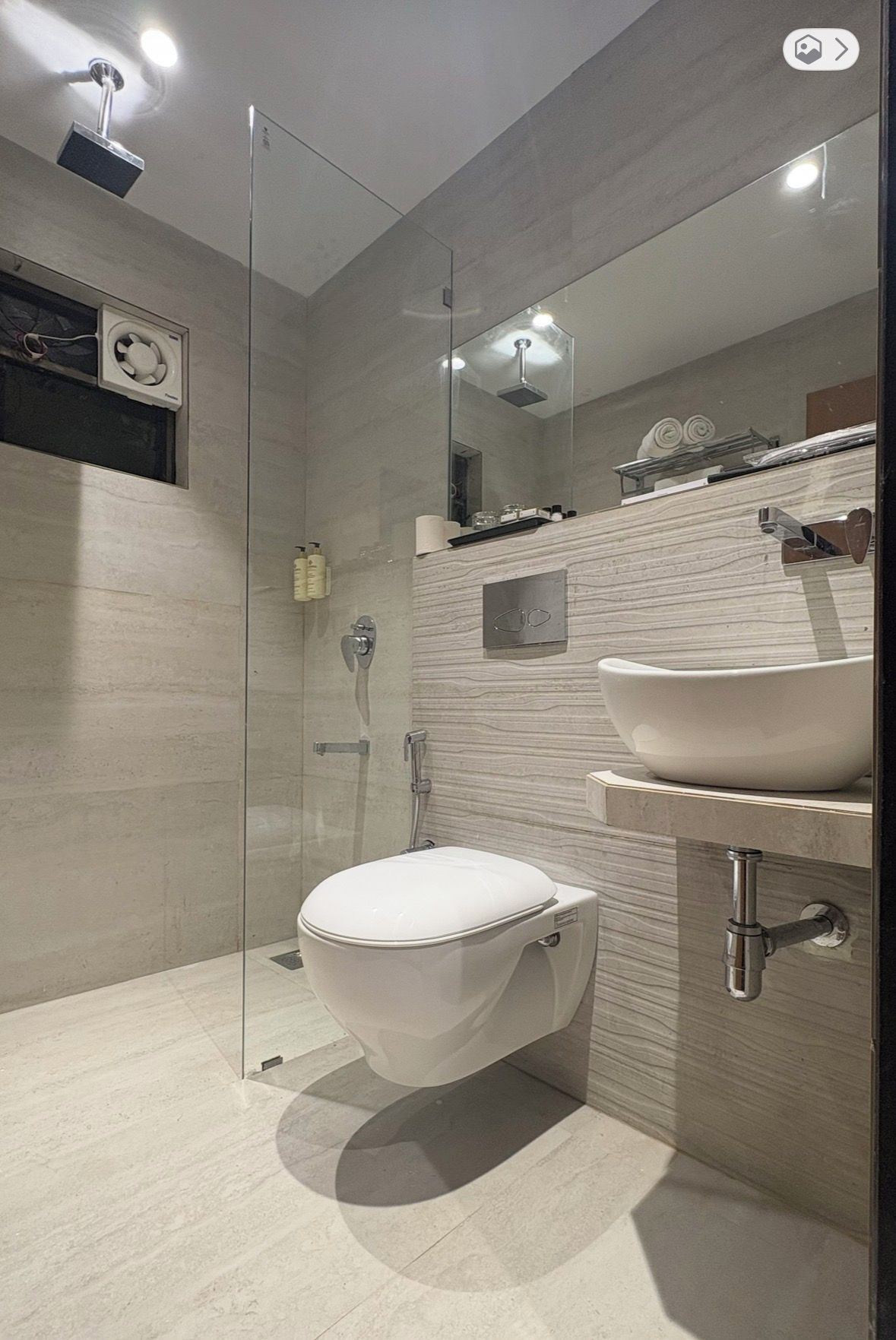 A modern bathroom with a glass-enclosed shower, a white toilet, and a sink with a mirror above.