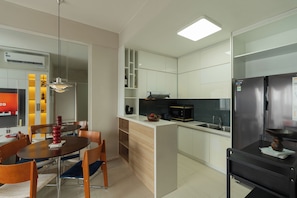 A modern kitchen with white cabinets, a stainless steel refrigerator, and a dining area with a table and chairs. - Kaleido Home 2BR 75m2 Landmark 81 View, Bathtub, The Sun Avenue, Pool & Gym (Thành phố Hồ Chí Minh)