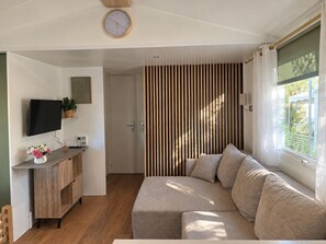 A modern living room with a sofa, a flat-screen TV, a wooden cabinet, and a striped wall. - New Listing (Vias)
