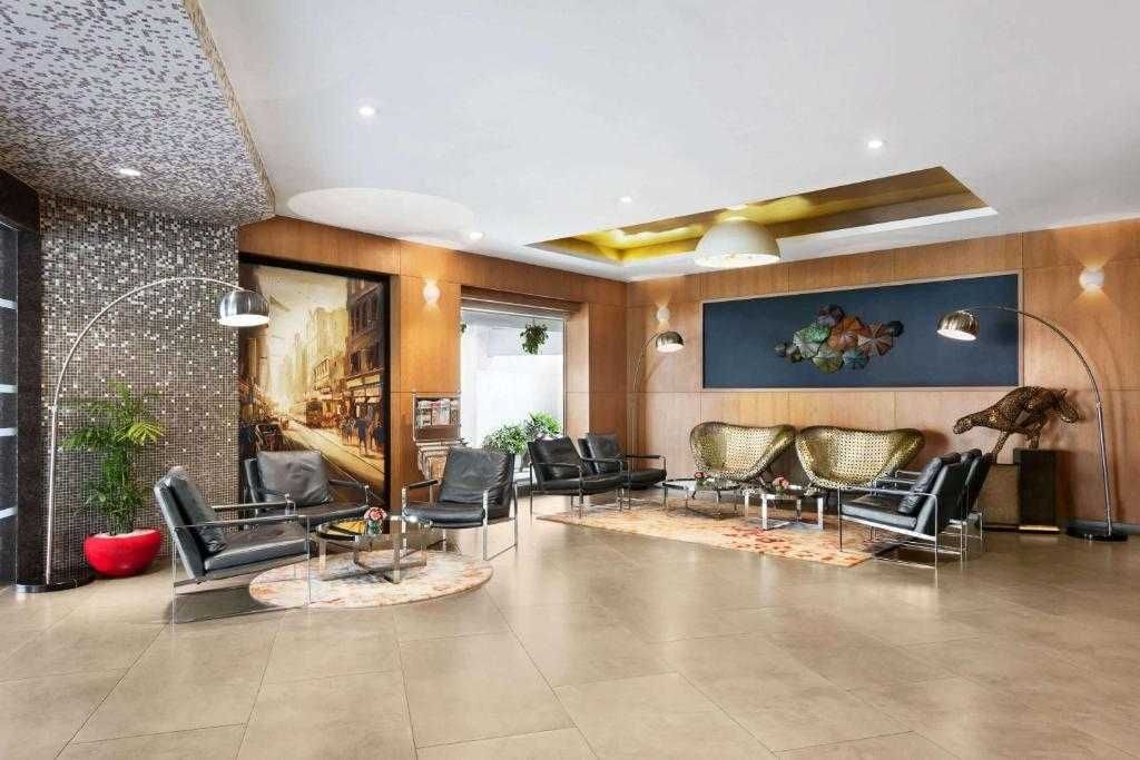 A modern lobby with a seating area, a large painting, and a sculpture.
